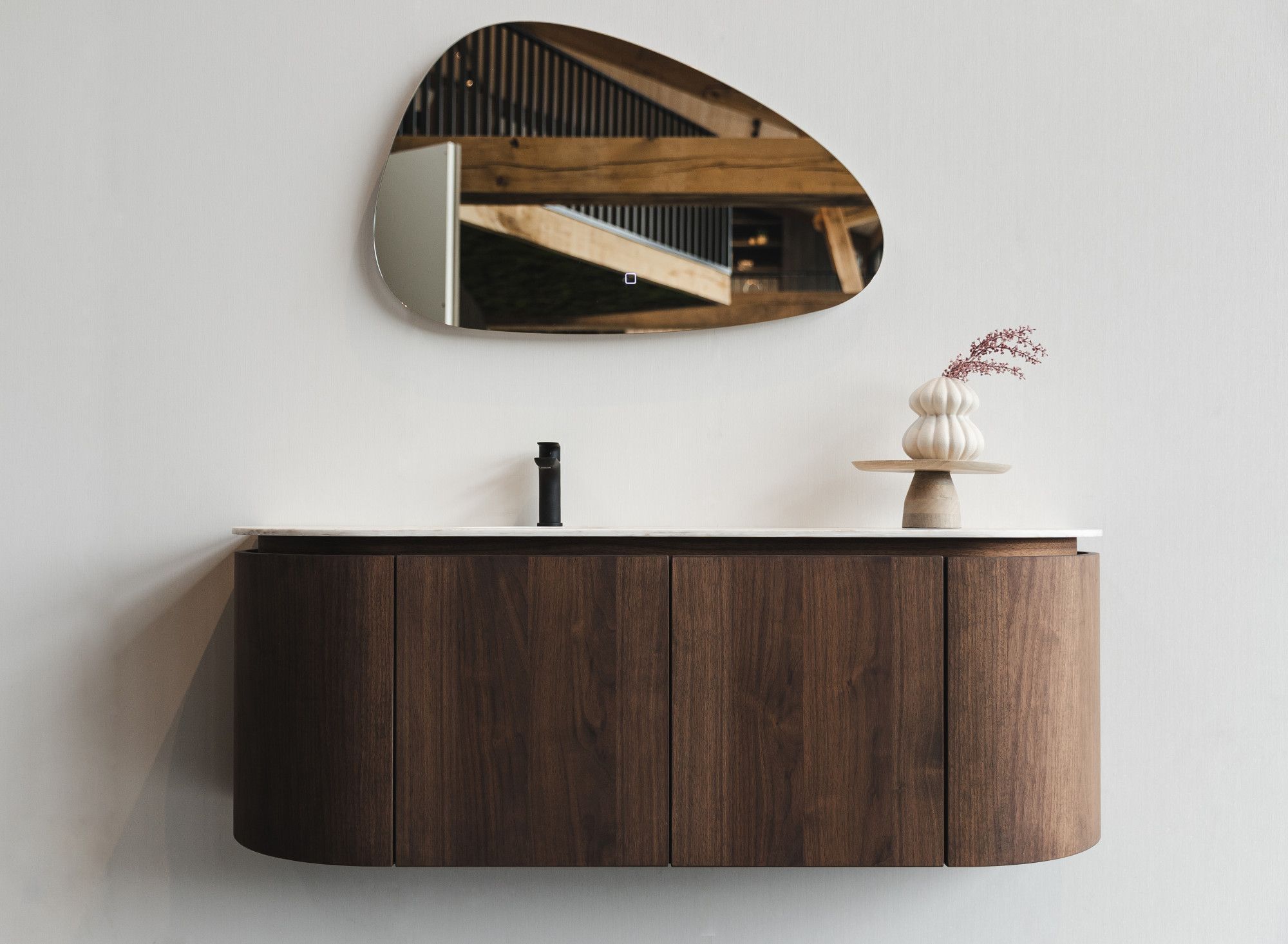 Badkamermeubel in showroom van notenhout met organische spiegel en zwarte kraan Badkamermeubel in showroom van notenhout met organische spiegel en zwarte kraan