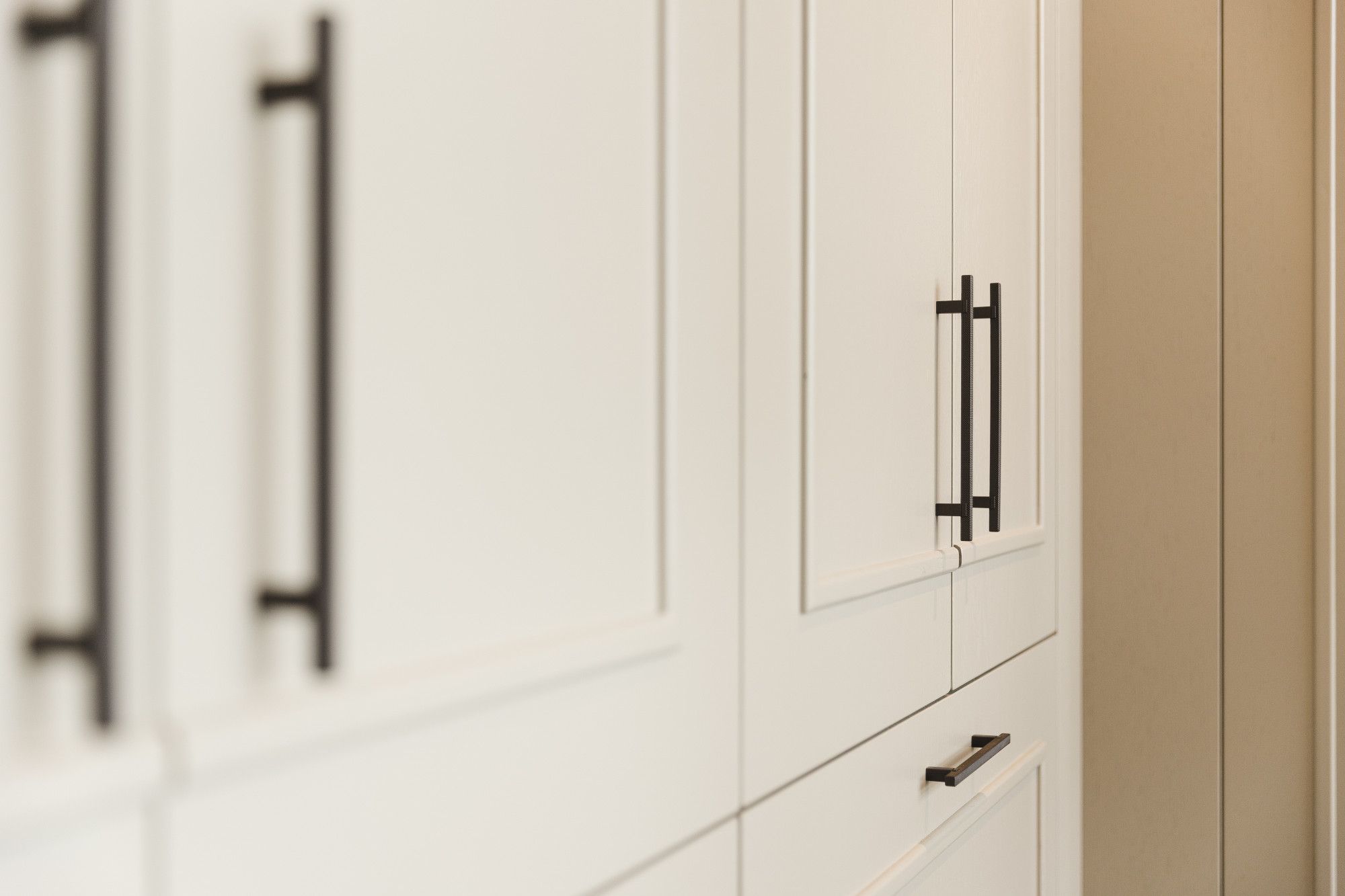 Detail van maatwerk kast met zwarte grepen en lijst op de deuren